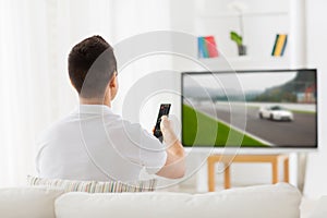 Man with remote watching motorsports on tv at home photo