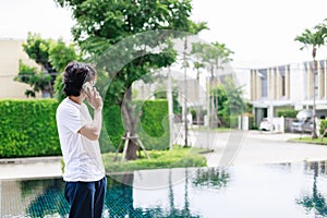 A man remote work during vacation and use smartphone near the swimming pool in resort hotel