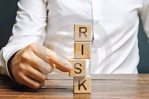 Man removes blocks with the word Risk. The concept of reducing possible risks. Insurance, stability support. Legal protection of photo