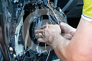 A man removes the door card to find a problem in the inoperative power window and repair it. Car repair at a service station