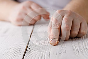 Man removes a gold wedding ring from his finger. Concept of family quarrel, divorce or betrayal