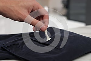 Man removing chewing gum from black jeans indoors, closeup. Space for text