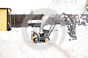 a man removing and cleaning the road from snow with a gasoline snow blower