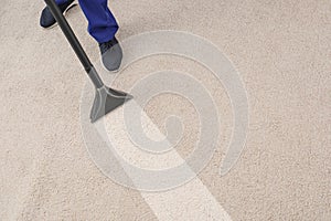 Man removing dirt from carpet with professional vacuum cleaner in room