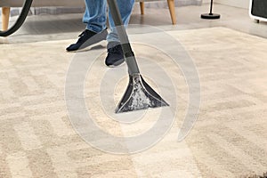 Man removing dirt from carpet with vacuum cleaner