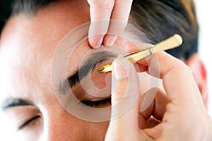 Man removing eyebrow hairs with tweezing.