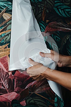 man removing a floral wallpaper from a wall