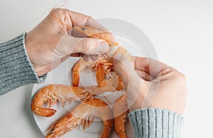 man removing the head of a cooked prawn