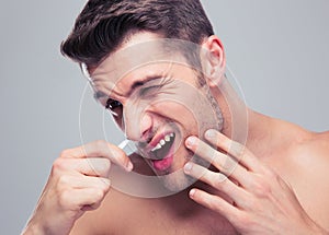 Man removing nose hair with tweezers