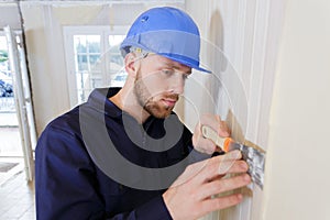 man removing plaster from wall indoors