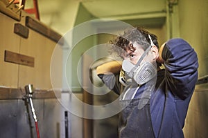 Man removing a protective respirator mask as he finishes his spray painting job