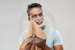 Man removing shaving foam from face by towel
