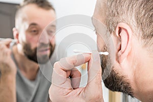 Man removing wax from ear using Q-tip