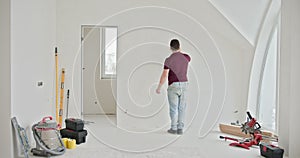 Man Renovating and Painting Walls in a Bright Modern Apartment