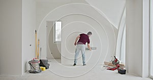 Man Renovating and Painting Walls in a Bright Modern Apartment