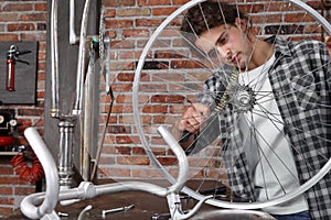 Man repair the bicycle in garage workshop on the workbench with tools, with the brush on the wheel, diy concept, red bricks