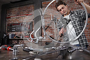 Man repair the bicycle in garage workshop on the workbench with tools, with the brush on the wheel, diy concept, red bricks