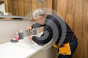 Man repair and fixing leaky faucet in bathroom.