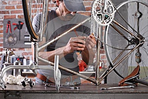 Man repair the vintage bicycle in garage workshop on the workbench with tools, diy concept photo