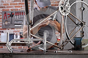 Man repair the vintage bicycle in garage workshop on the workbench with tools, diy concept