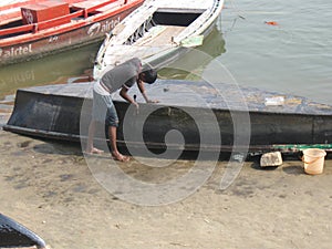Man repairing boat Assi Ghat Varanasi India