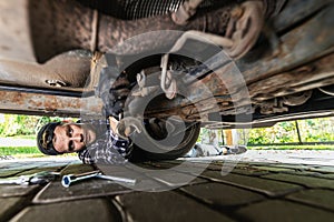 Man repairing bottom of rusty old car. mechanic working