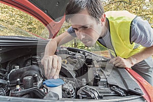 Man is repairing car and checking engine coolant