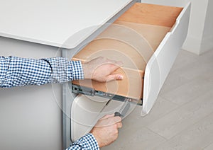 Man repairing chest of drawers in room