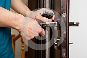 a man repairing a door knob. locksmith fixing a wooden door