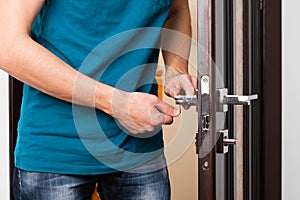 a man repairing a door knob. locksmith fixing a wooden door