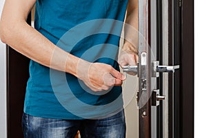 a man repairing a door knob. locksmith fixing a wooden door