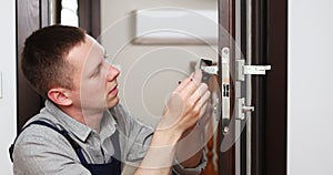 a man repairing a door knob. locksmith fixing a wooden door.