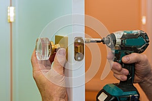 Man repairing the doorknob closeup of worker hands installing new door locker