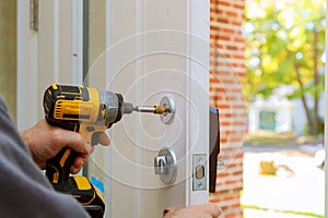 man repairing the doorknob. closeup of worker& x27;s hands installing new door locker