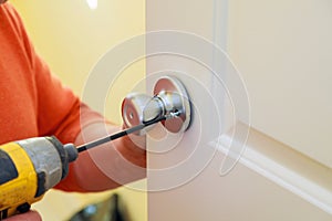 Man repairing the doorknob. closeup of worker& x27;s hands installing new door locker