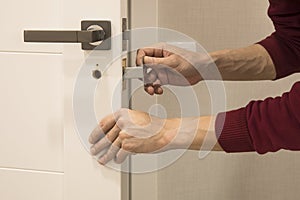 man repairing the doorknob. closeup of worker& x27;s hands installing new door locker