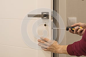 Man repairing the doorknob. closeup of worker`s hands installing new door locker