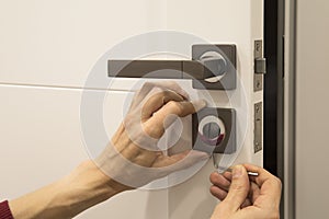 man repairing the doorknob. closeup of worker& x27;s hands installing new door locker