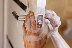 Man repairing the doorknob. closeup of workers hands installing new door locker