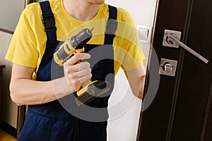 a man repairing a doorknob. Handyman repair the door lock in the room.