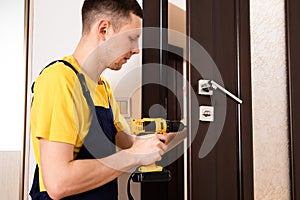 a man repairing a doorknob. Handyman repair the door lock in the room.