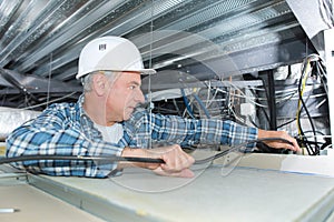 Man repairing electrical wiring on ceiling