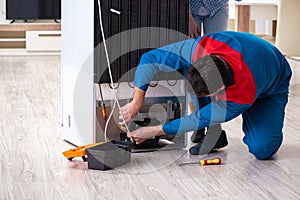 The man repairing fridge with customer