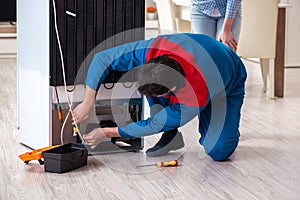 The man repairing fridge with customer