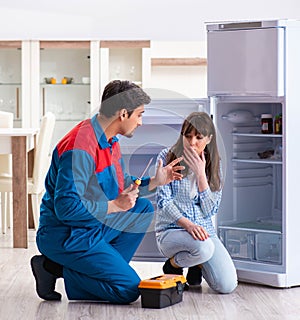 Man repairing fridge with customer