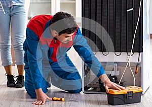 Man repairing fridge with customer