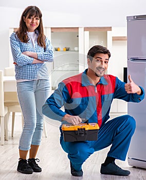 Man repairing fridge with customer