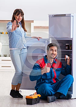 Man repairing fridge with customer