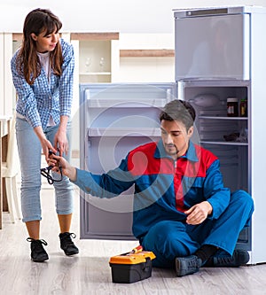 Man repairing fridge with customer