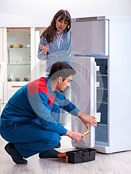 Man repairing fridge with customer